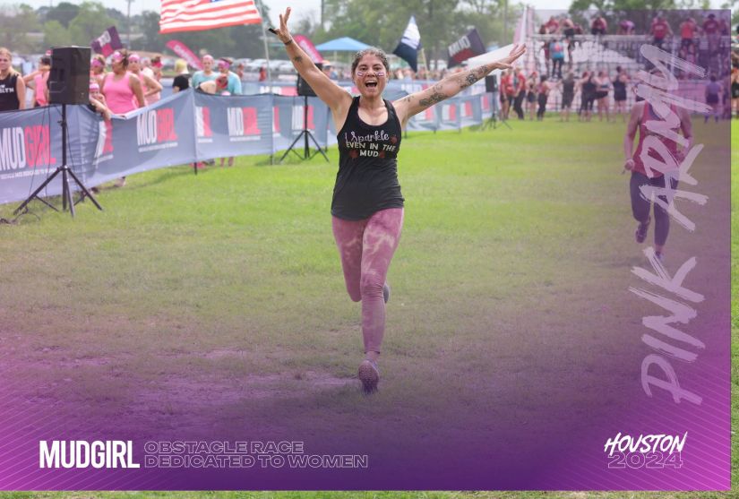 Carola running through finish line mud girl with arms in the air