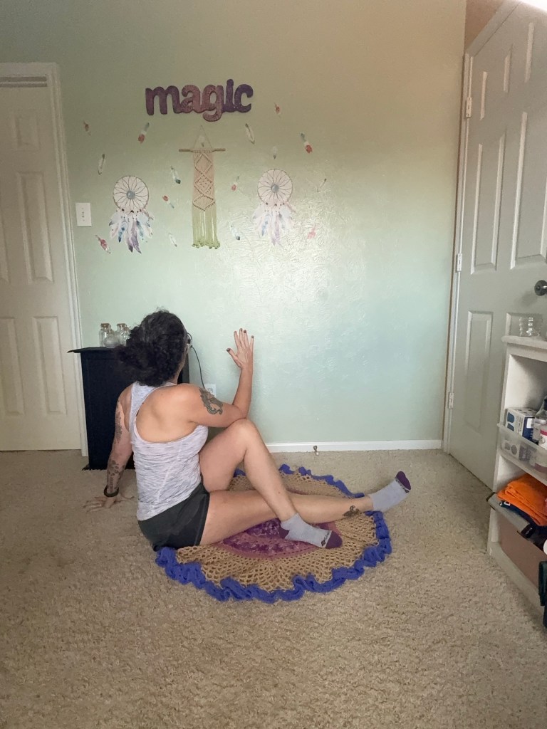 Girl doing Spinal twist facing the wall and showing elongated spine.