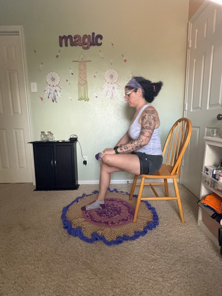 Girl sitting on chair with left ankle over right thigh.