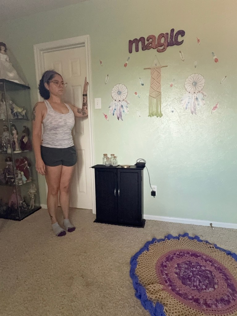 Girl standing in doorway with left forearm on the doorframe.