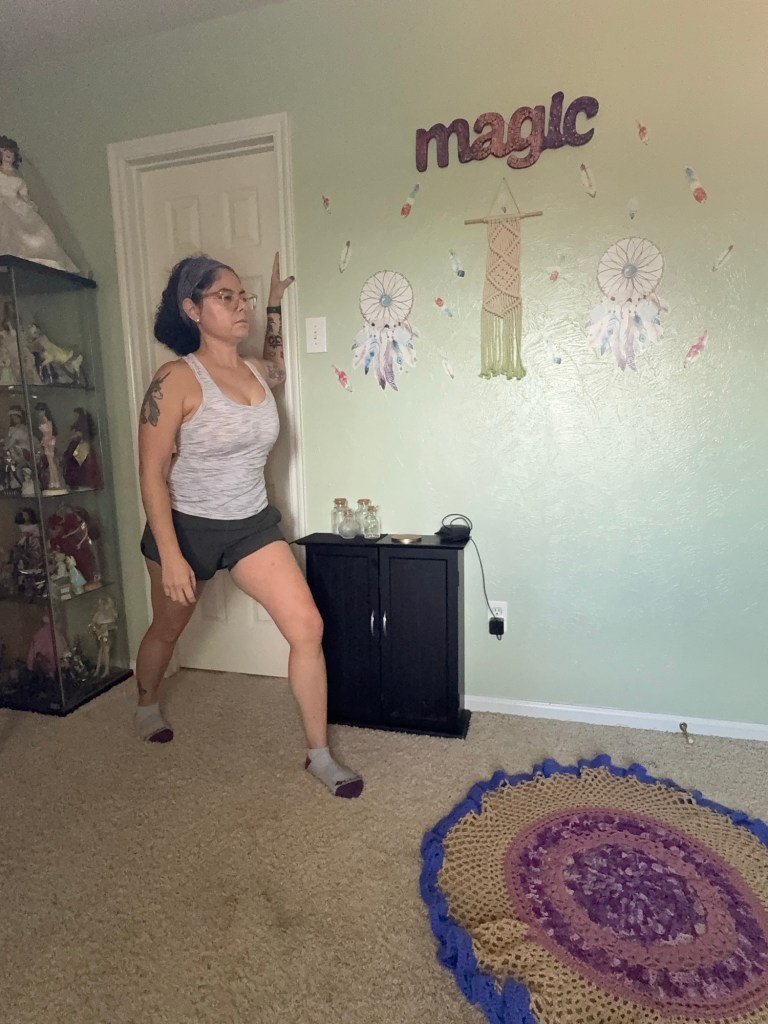 Girl standing in doorway with left forearm on the doorframe lunging forward with left leg towards front.